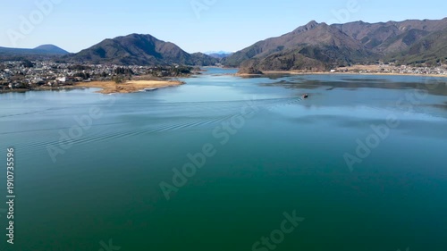 Wallpaper Mural Wide view of Lake Kawaguchi with calm water and a small boat in the distance. Peaceful Japanese landscape framed by mountains and soft daylight. Torontodigital.ca