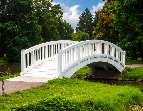 Picturesque white bridge in a lush green park setting.