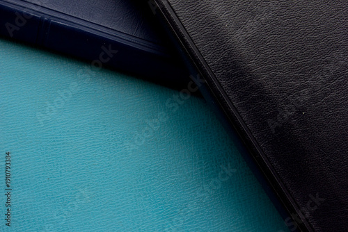 Close-up full frame photo of a stack of black and blue-covered Bibles, copy space background and texture.