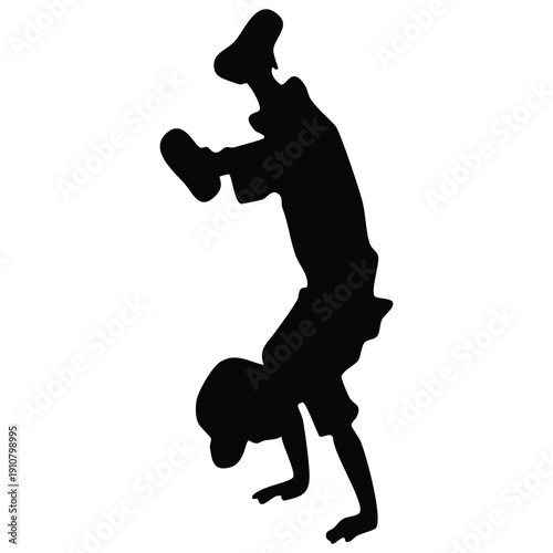 Silhouette of a young boy performing a handstand breakdance move
