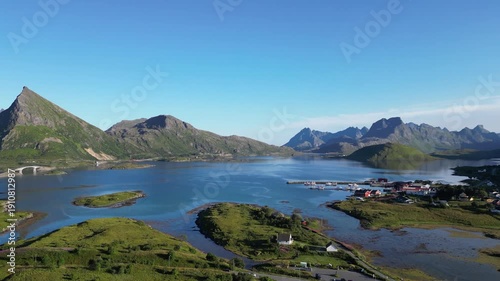 Aerial view of the Fredvang Bridges with the striking peak of Volandstind in the background, followed by a camera pan toward the village of Fredvang. Lofoten Islands in Norway.