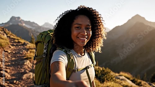 Joyful Ascent: A woman hiker with curly hair smiles brightly on a sunlit mountain trail. She's carrying a backpack, with majestic peaks in the background, exuding adventure and serenity. 