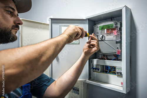 фотографія Electrician Installing electricity counter in switchbox