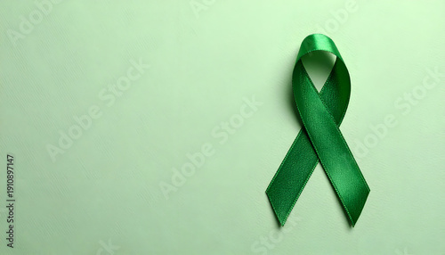 Green awareness ribbon on a pastel green background, minimalist concept for mental health and medical support. Generative AI.