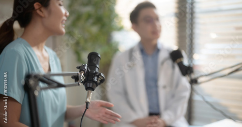 Asian male and female doctors hosting medical podcast together.