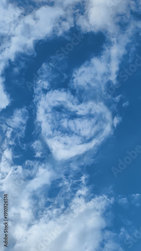 Clouds in the sky form a heart shape during a bright day, symbolizing love and connection in a serene atmosphere