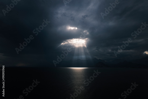 Dramatic light beams between clouds above ocean