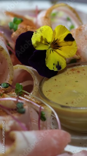 Meat, lard, sliced, mustard, garnished with edible flowers on a plate in a restaurant serving