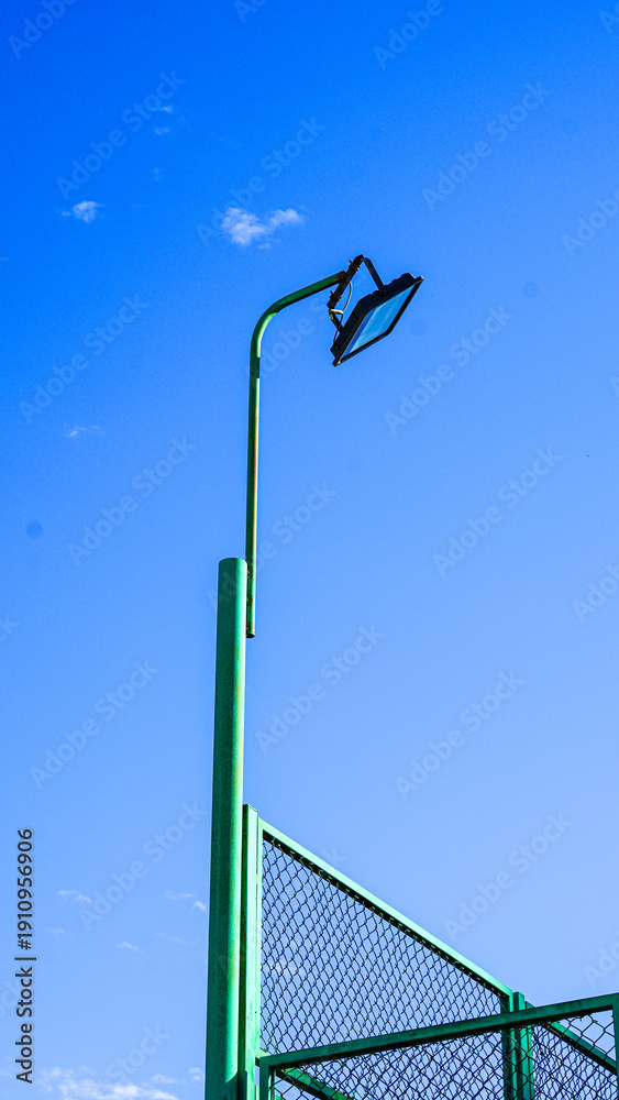 Obraz premium Green sports field light pole against clear blue sky