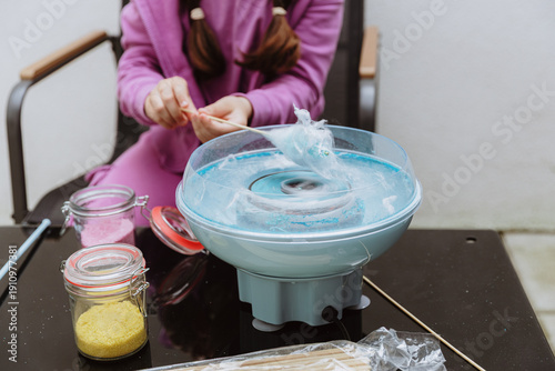 Vászonkép The girl makes cotton candy herself in the garden.
