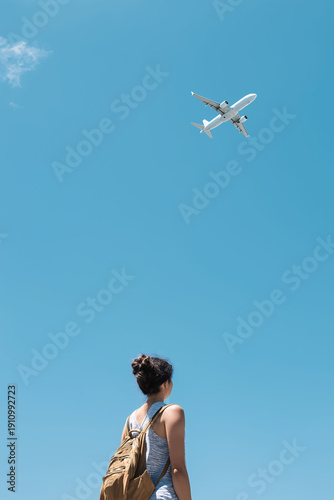 Traveler gazing up at airplane in blue sky outdoor scene vertical composition