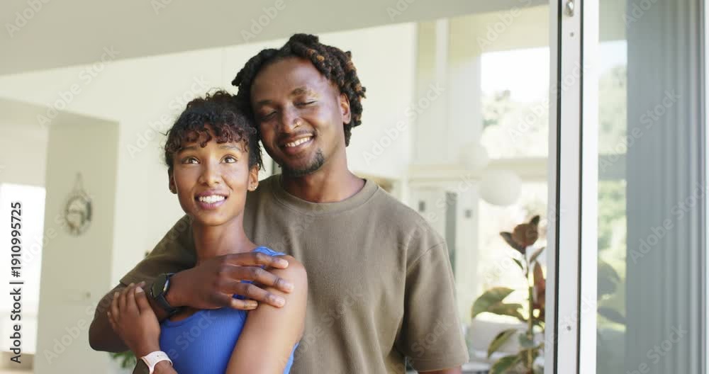 African American couple hugging at home by sliding door, man reaching ...
