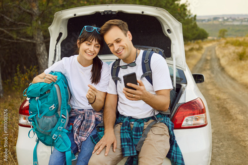 Fotografía Travel adventure of happy couple sitting by car with smartphone to check map and geolocation for planning route, take selfie of vacation for social media