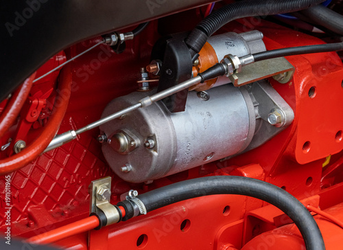 Foto Close-up of a modern tractor electric starter motor on a red diesel engine