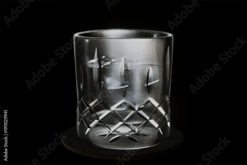 Crystal glass tumbler with ice cubes on black background