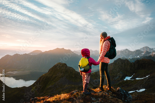 Family hiking in Norway mother and child climbing mountains, parent and kid travel with backpacks enjoying nature views together holding hands lifestyle active summer vacations tour in Lofoten islands