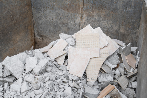 Discarded ceramic tiles and masonry rubble in a metal waste container