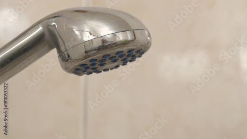 Turning on the water in shower. Water flows out of the shower head. Shower head in bathroom, chrome faucet, close-up shot
