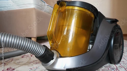 Dust is spinning in yellow container of vacuum cleaner, video with sound. Cleaning carpet in room with vacuum cleaner
