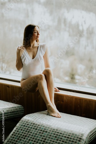 Woman sits by window in swi...