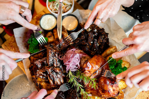 Fotografie Top view of friends sharing a large grilled meat platter with ribs, roasted chic