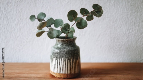 Simple and Elegant Eucalyptus Arrangement in a Rustic Pot on a Minimalist Wooden Surface with Textured Background