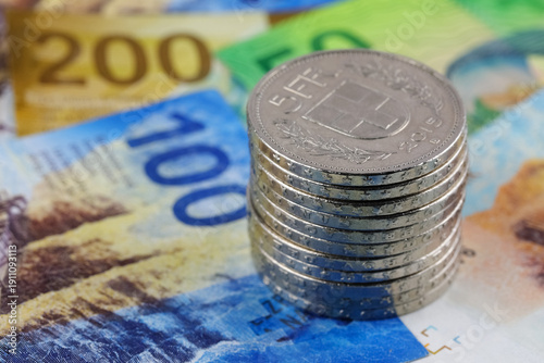 Schilderij op canvas A heap of coins sits on Swiss banknotes