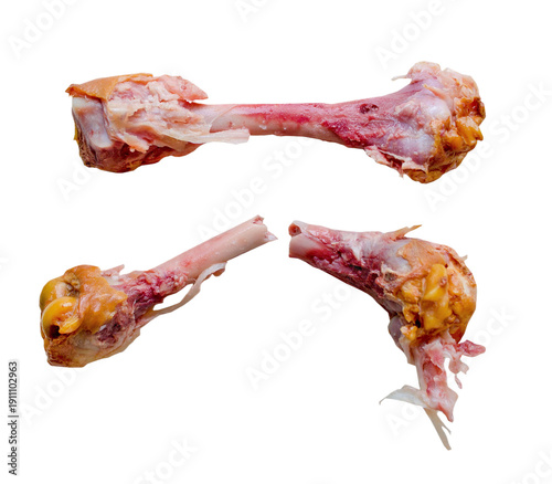 Three chicken bones lay on a white surface. The bones show signs of being gnawed on, with bits of meat and fat still attached. The scene captures a common leftover from a meal