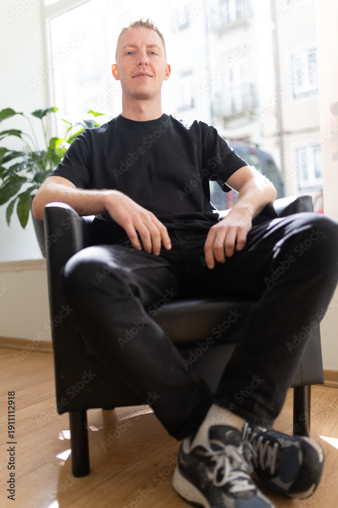 Fototapeta premium Young man sitting chair looking at camera