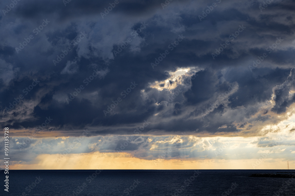Obraz premium Dramatic storm clouds over ocean at sunset