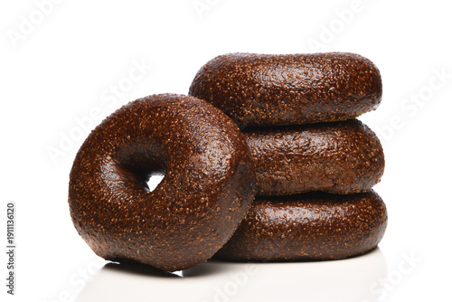 Photography Closeup of a Pumpernickel Bagel leaning on a stack of similar bagels on white