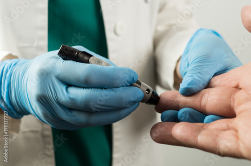 Bild auf Leinwand A medical professional performing a finger prick test on a patient using a lanci