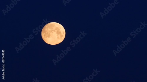 Full moon setting in the dark blue night sky