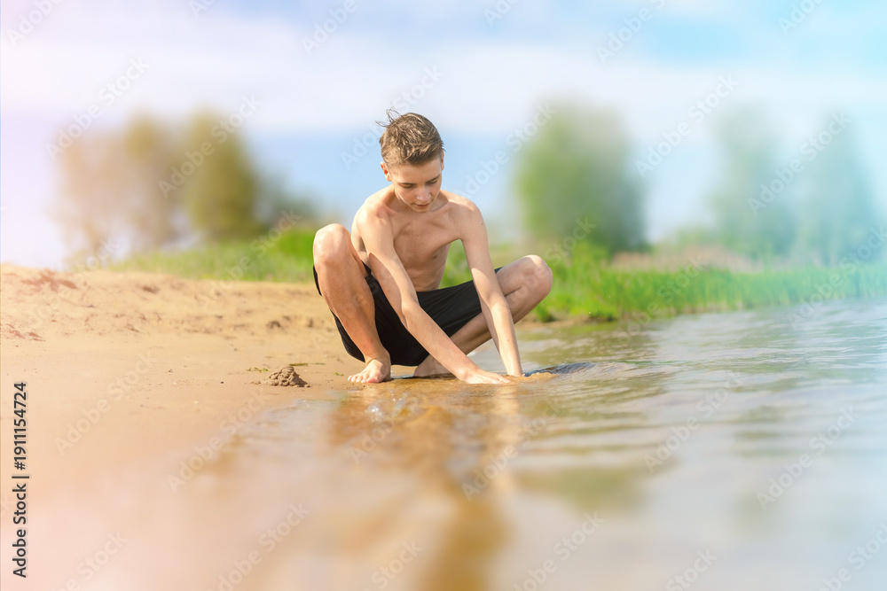 Fototapeta premium Boy Playing with Sand at Lakeside on a Sunny Day