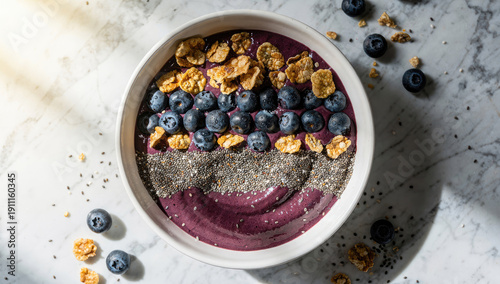 Top View of a Healthy Blueberry Smoothie Bowl with Chia Seeds and Cornflakes on a White Marble Surface, Nutritious Vegan Breakfast Concept