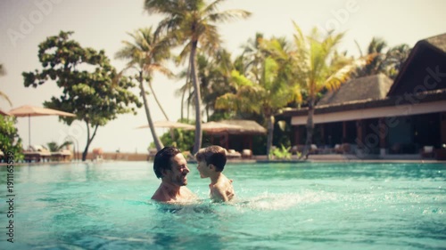 Happy father and son enjoy playful splashing and bonding in a luxurious resort pool
