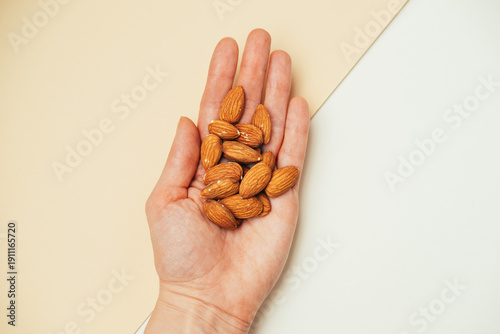 Tablou pe pânză Image Features Hand Holding Almonds To Illustrate Controlled Healthy Snack With