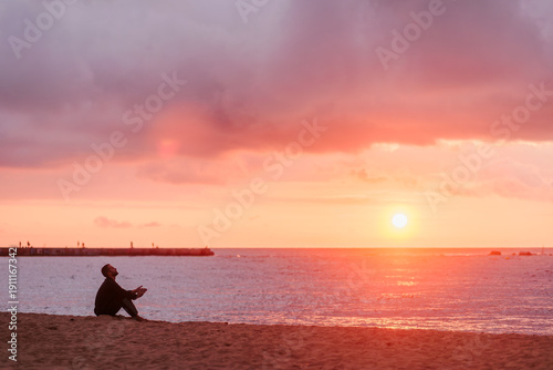 Young man enjoying solitude and inspiration on beach watching sunset