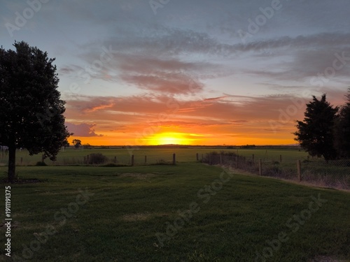 a field with a fence and a sunset