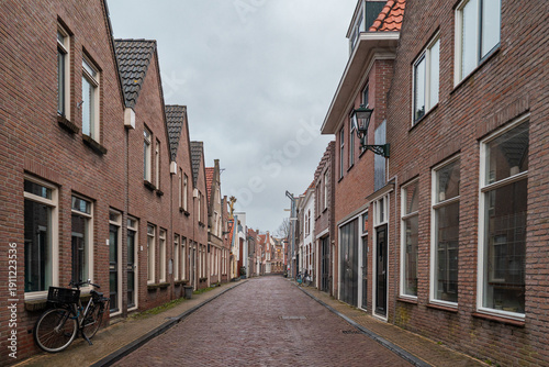 Alkmaar street with traditional brick houses, residential buildings lining cobbled alley, bicycle parked on urban sidewalk