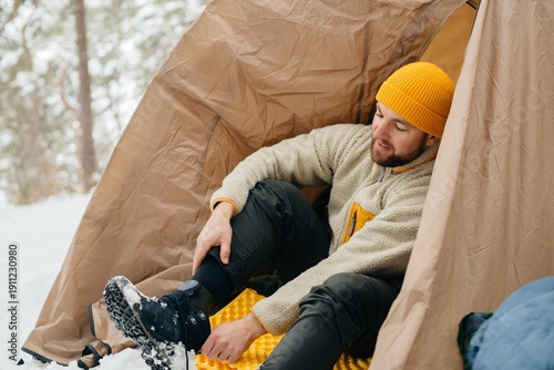 Quadro su tela Man putting on winter boot inside tent camping