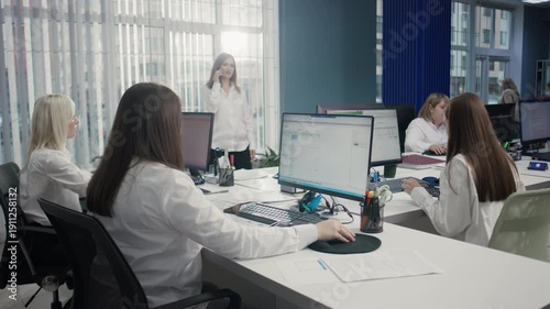 Office footage, high resolution: Several Caucasian women working at the office. One colleague is standing and talking on the phone, while others are focused on their computers. 4K.