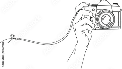 Hand holding vintage camera with attached strap and small object