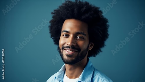 Wallpaper Mural Young Man With Afro Hair and Beard Smiles Gently Against a Blue Background, Studio Portrait Torontodigital.ca