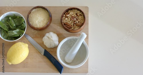 Camera is zooming to center cutting board with basil, cheese, garlic on counter, copy space