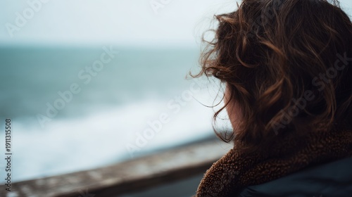 Woman with brown hair is looking out at the ocean