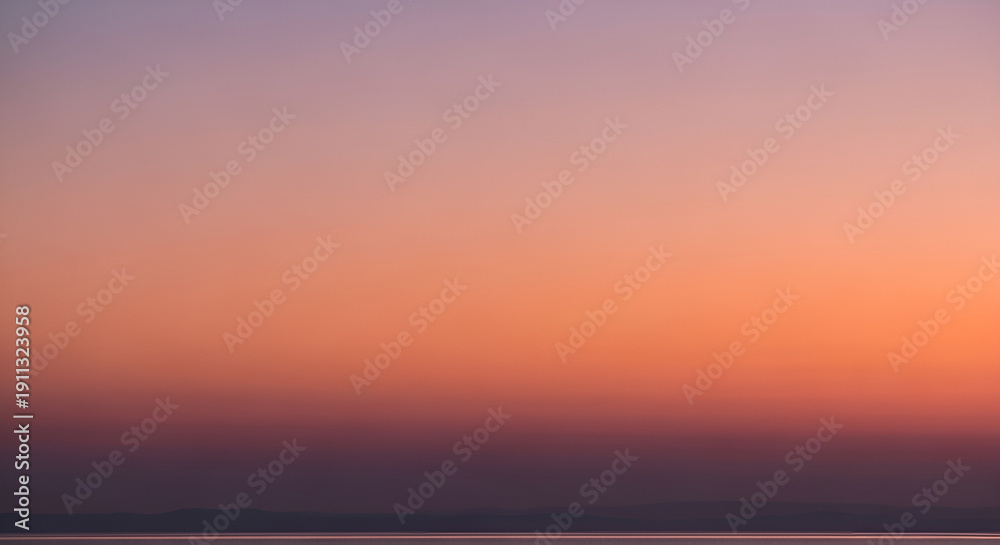 Fototapeta premium Sunset over serene landscape with vibrant sky and silhouette of hills