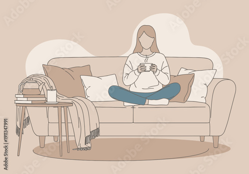 Woman sitting on a comfortable couch holding a warm beverage enjoying a moment of rest indoors
