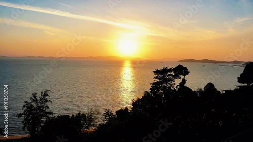 Beautiful orange sunset over the sea and beach with evening clouds reflecting on the ocean waves at the horizon