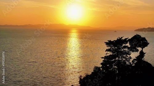 Beautiful orange sunset over the sea horizon with clouds reflecting on calm ocean waves by the beach coast at evening dusk